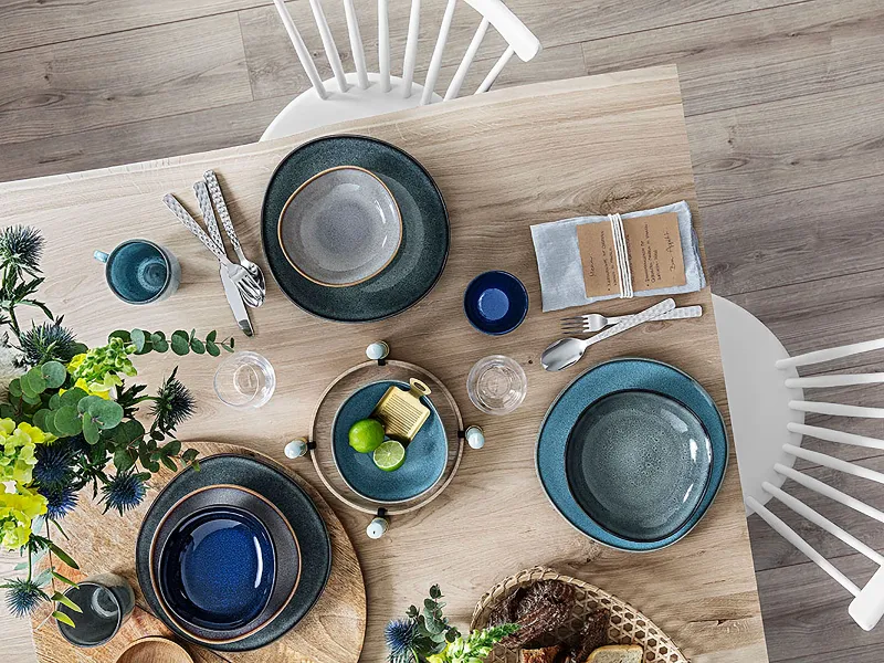 A wooden table with Villeroy & Boch Lave plates on top.