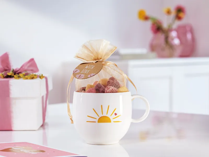 With Love cup with a yellow sun and heart pattern prepared as a gift with sweets.