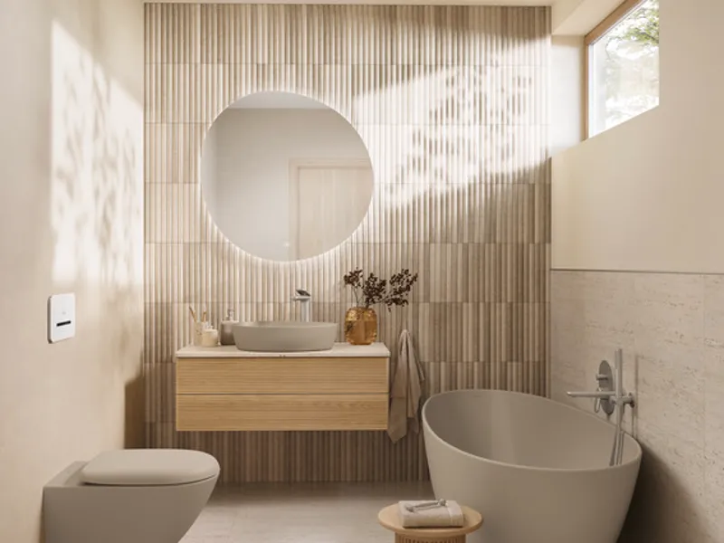 Bagno naturale beige con elementi della collezione Antao Bagno luminoso in tonalità beige naturali con vasca freestanding, specchio rotondo e lavabo da appoggio della collezione Antao, arricchito da texture in legno e luce naturale.
