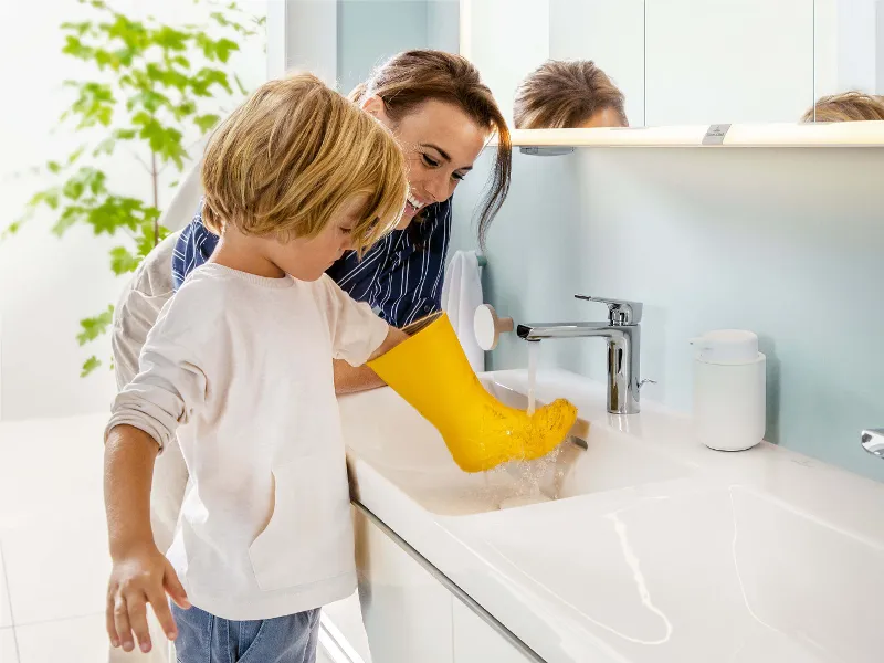 A woman and a child washing a yellow wellington boot in a Subway 3.0 washbasin.