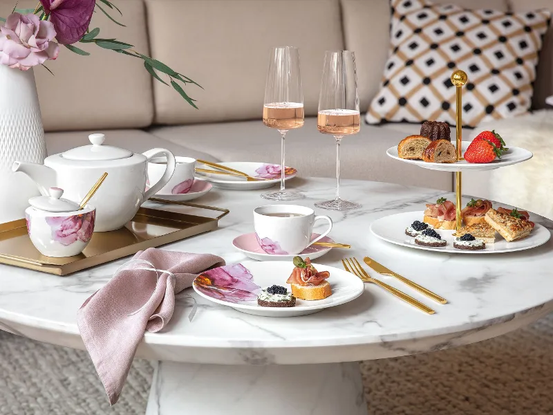 Elegant afternoon tea setting with snacks and rosé wine on a marble table, served on Villeroy & Boch Rose Garden crockery.