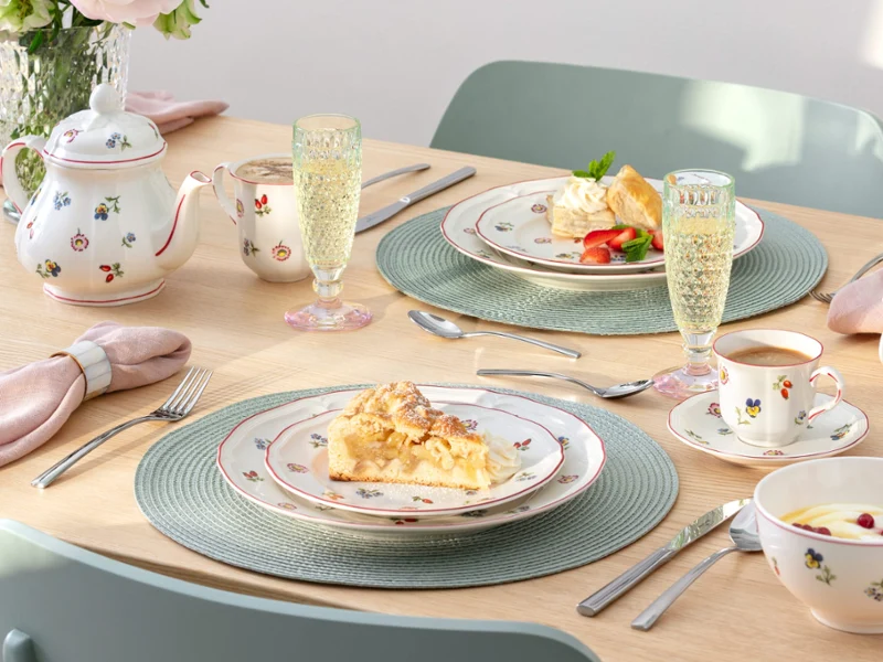 Petite Fleur as a floral coffee & cake set A set table for two with dessert plates, teacups, a teapot, champagne glasses, and floral-patterned porcelain from Petite Fleur.