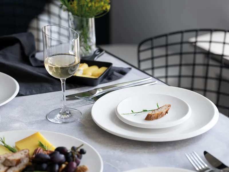 A small NewMoon plate with a baguette slice on a table.