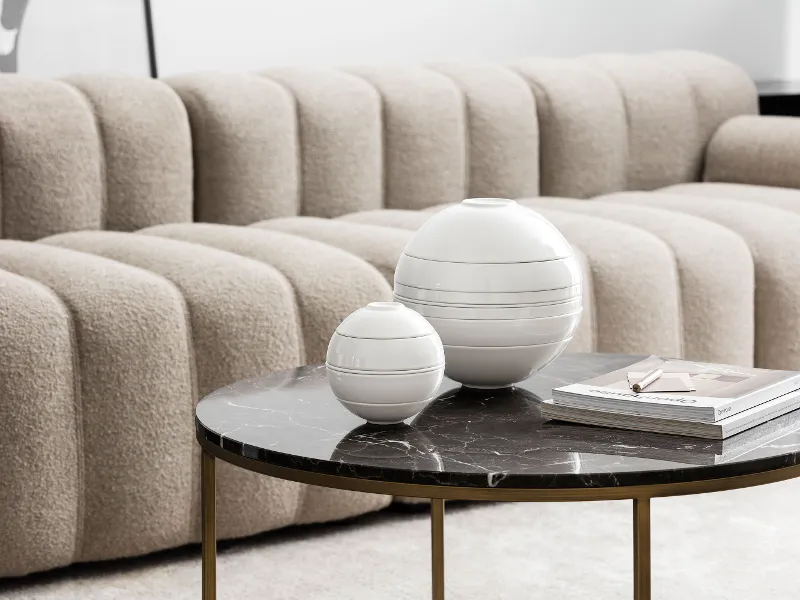 Ein modernes Wohnzimmer mit einem grauen, strukturierten Sofa und einem schwarzen Marmor-Couchtisch dekoriert mit der La Boule in verschiedenen Größen.