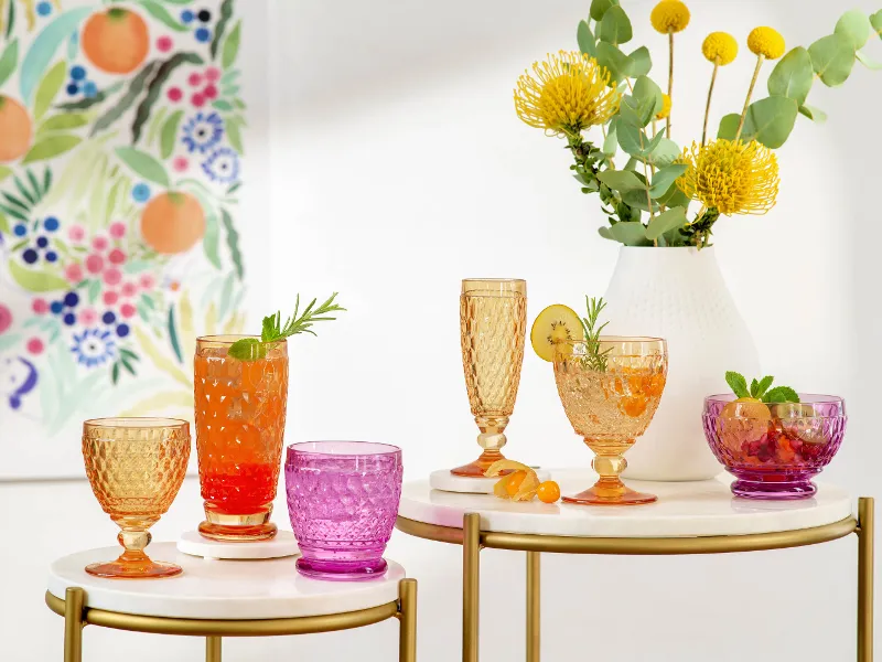 Colorful summer drinks in various Boston glasses on a chic serving table with a flower painting in the background.