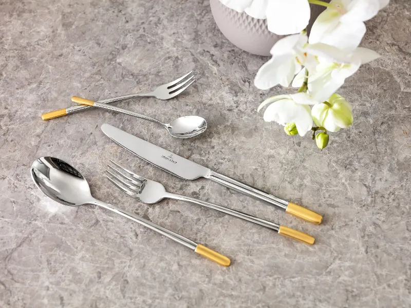 Elegant Ella cutlery set with gold details on a marble table top, together with a white orchid.