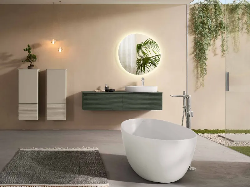 Et moderne, komplett baderom med møbler, porselen, lysspeil og badekar fra Villeroy & Bochs Antao-kolleksjon i naturlige farger og grønne planter.