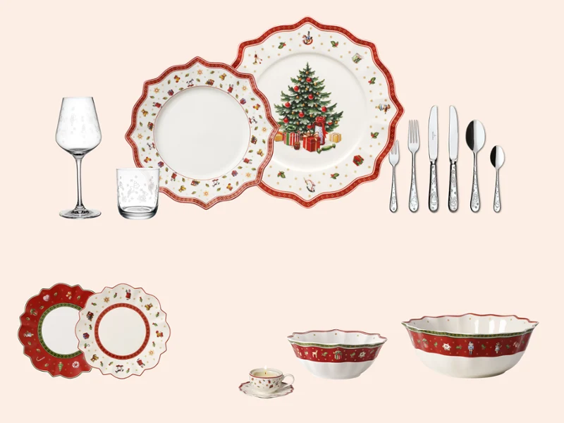 Christmas tableware set Christmas tableware set with plates, bowls, utensils, and glasses decorated with red accents and a decorated tree.