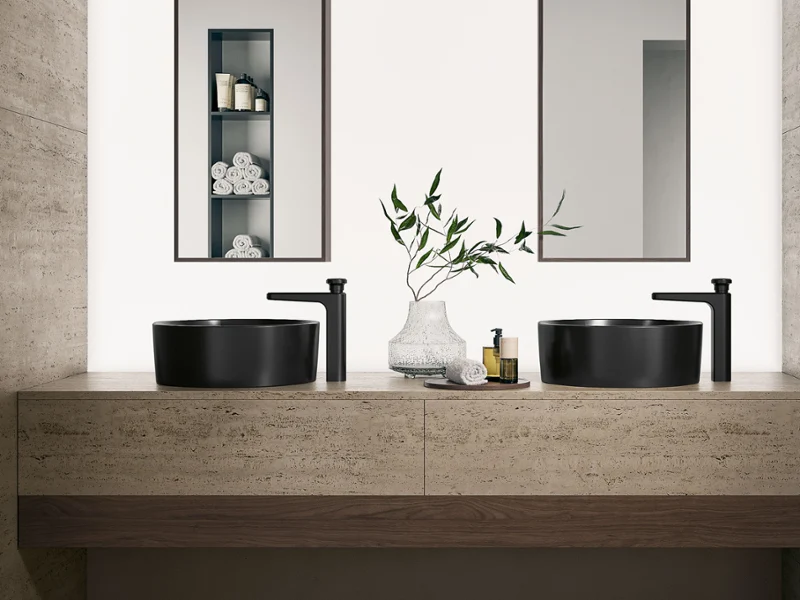 Modern bathroom with two black vessel sinks, black faucets, and a stone countertop. Two mirrors are mounted on the wall.