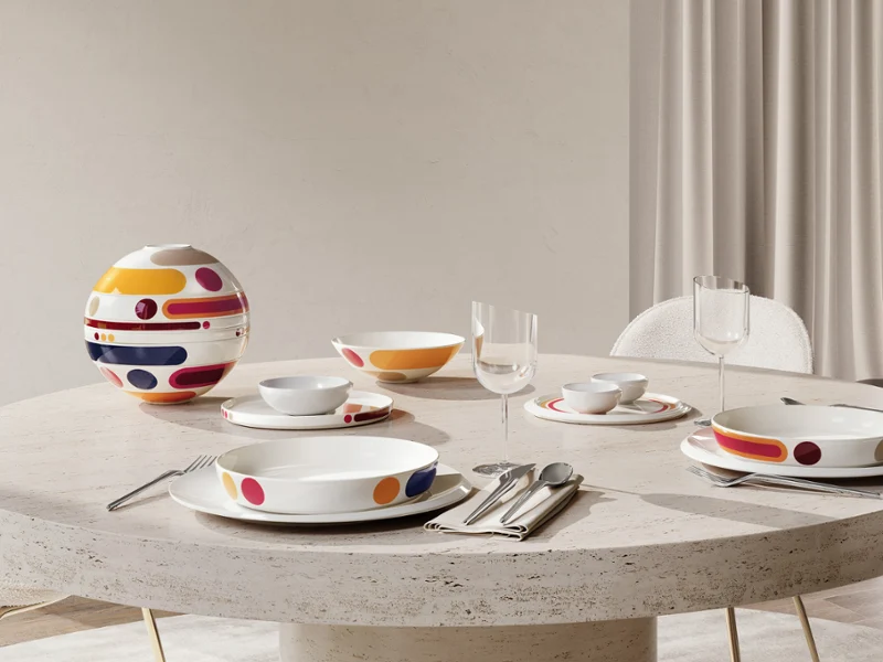 Ovale stenen tafel met modern, kleurrijk La Boule Miami. Eenmaal in elkaar gezet, eenmaal als losse artikelen, opgesteld bij een groot raam met een stoel.