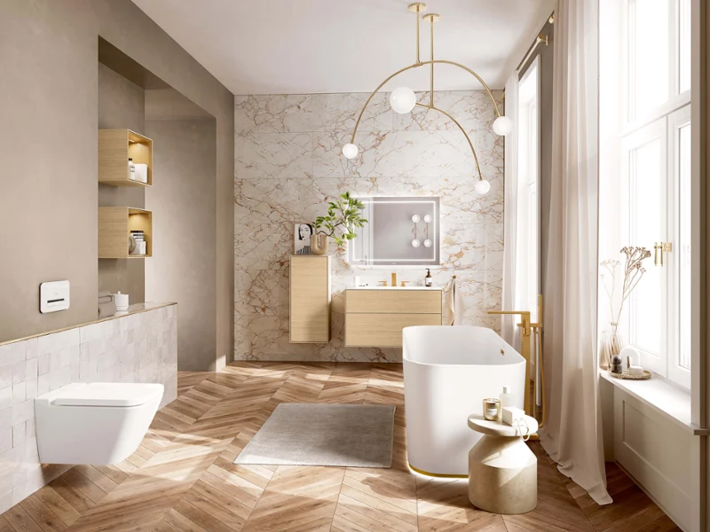 Biała wanna Finion w nowoczesnej łazience Wolnostojąca biała wanna ze złotymi bateriami Mettlach w nowoczesnej łazience z drewnianą podłogą i marmurową ścianą.