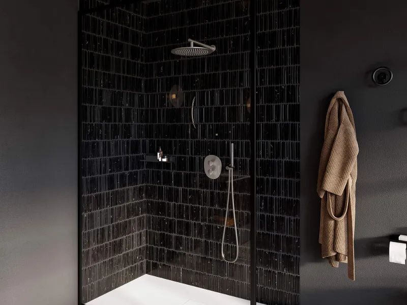 Modern walk-in shower with a glass screen, stainless steel taps from the Antao collection on black Metro tiles.