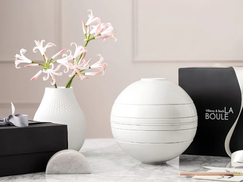 A white La Boule tableware set on a table with a black gift box behind it.