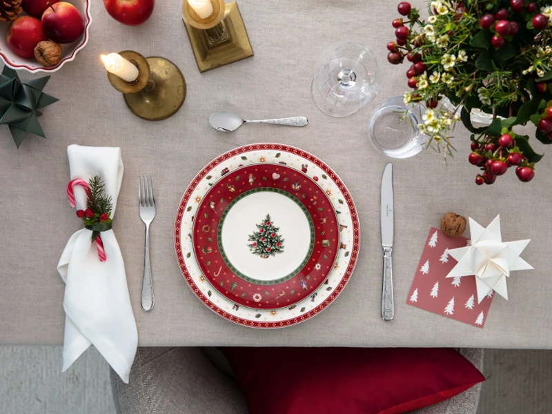 Table set for a feast with Toy's Delight Table set for a banquet with red and white plates, cutlery, candles and festive decorations, seen from above.