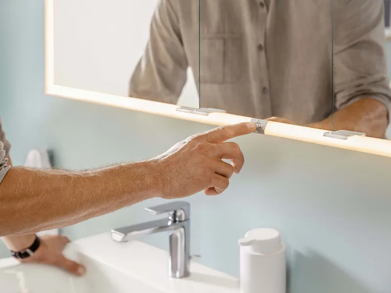 A man switching on the Subway 3.0 illuminated mirror in a bathroom.