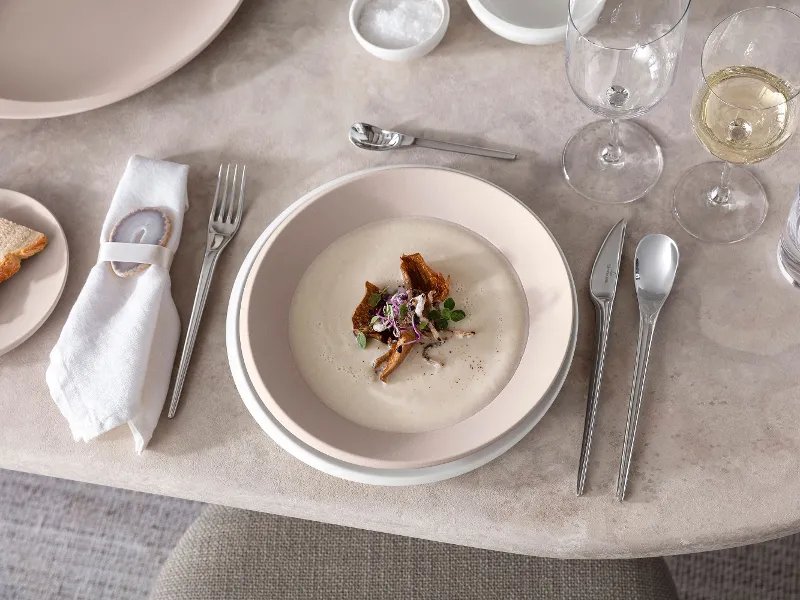 A table set with Villeroy & Boch NewMoon plates and cutlery with cream soup.