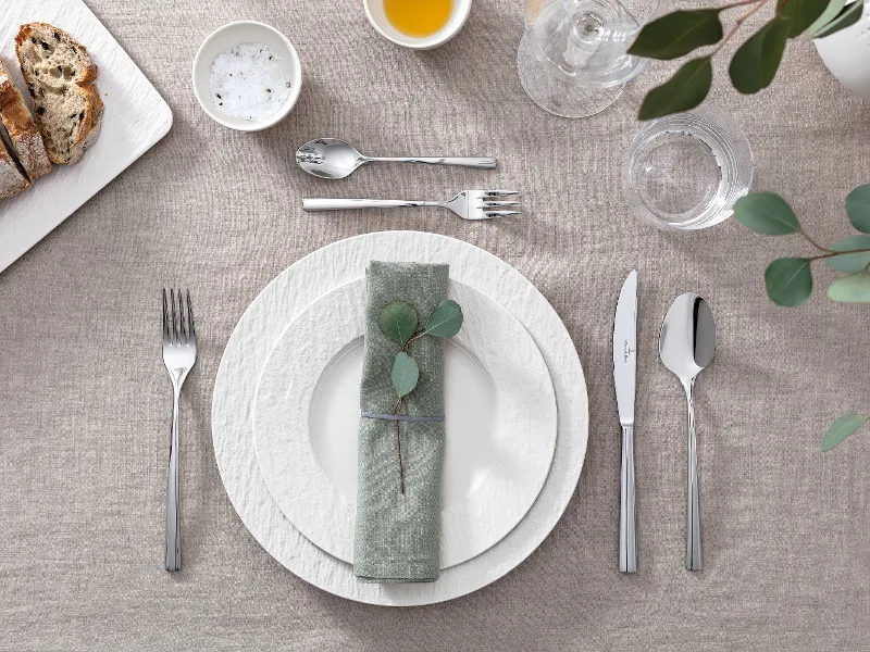 A table set with Villeroy & Boch white Manufacture plates, eucalyptus leaves and cutlery.