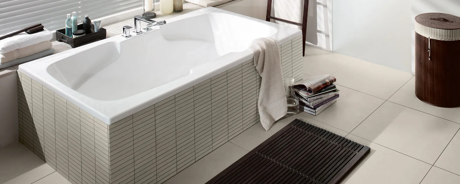 Et hvitt Colorado badekar i et beige baderom fra Villeroy & Boch med dekorert vinduskarm.