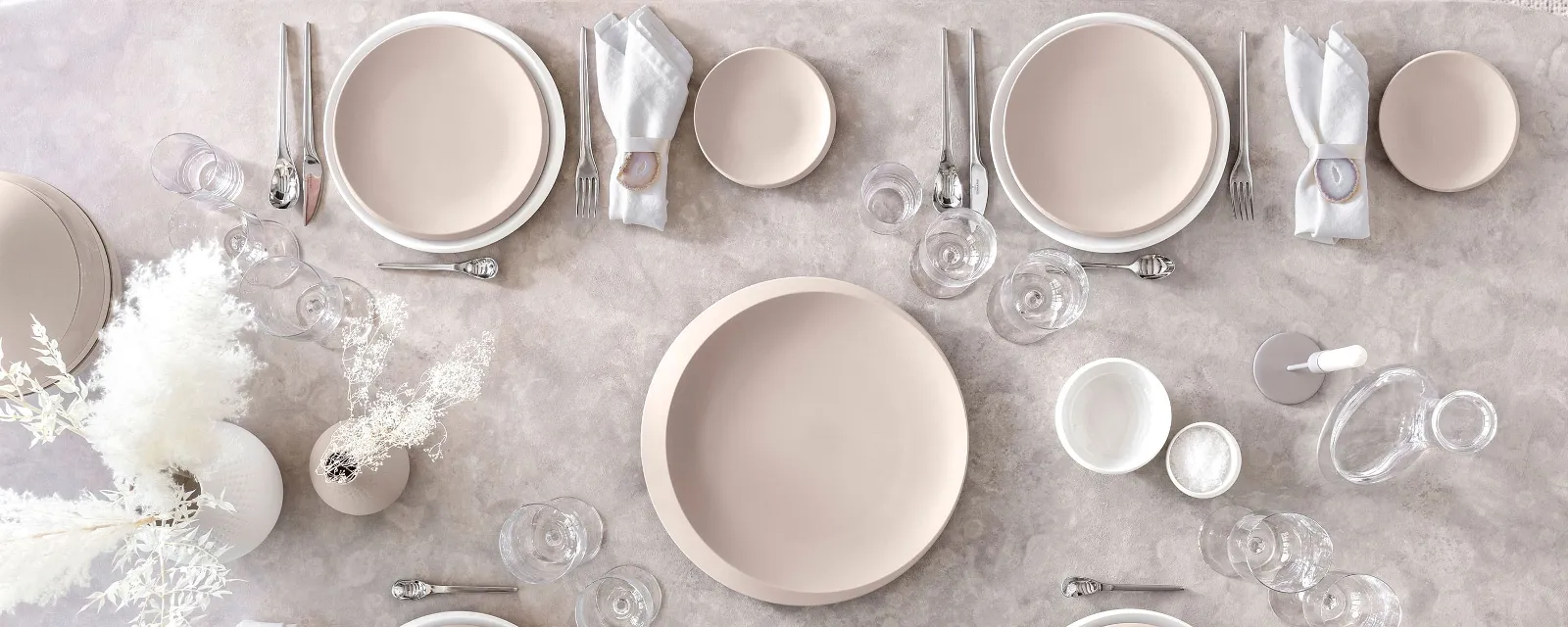 A table set with Villeroy & Boch NewMoon plates in beige and white along with cutlery and glasses.