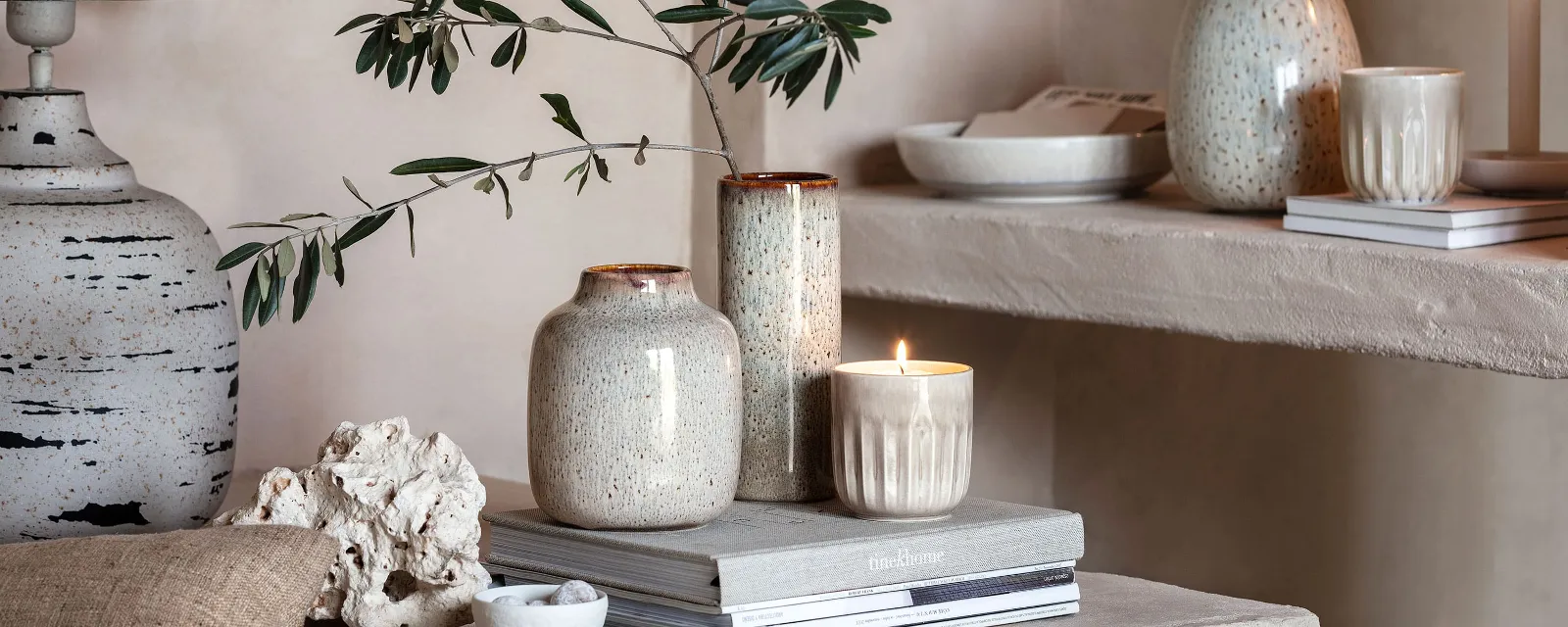 A living room with Perlemor scented candles, Lave vases and books on a shelf.