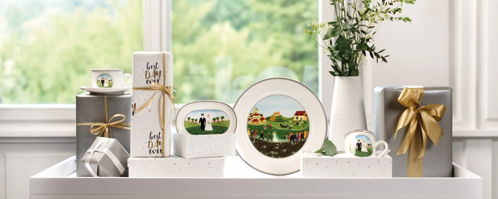 A  Villeroy & Boch Design Naif plate on a table with a vase of flowers, decorated gifts and picture frames in front of a window with a view of nature.