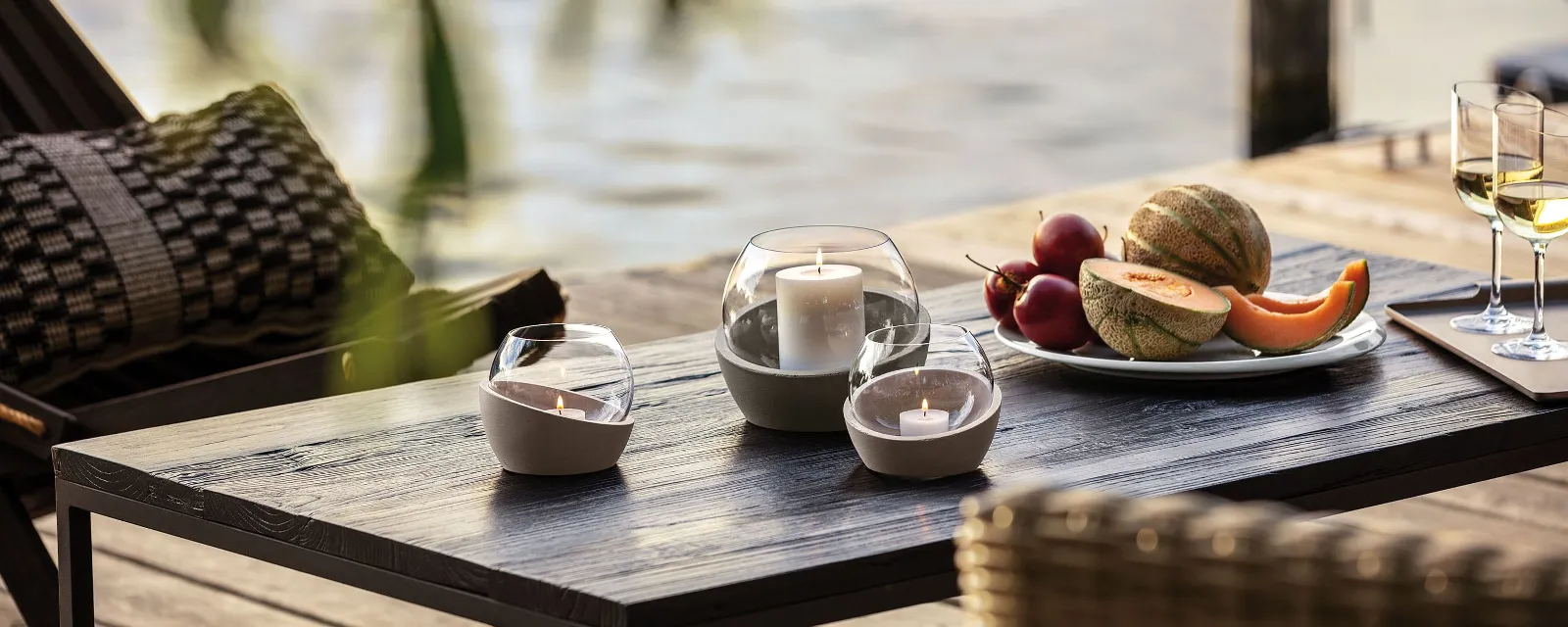 NewMoon hurricane lamps on a wooden table with fruit and wine.