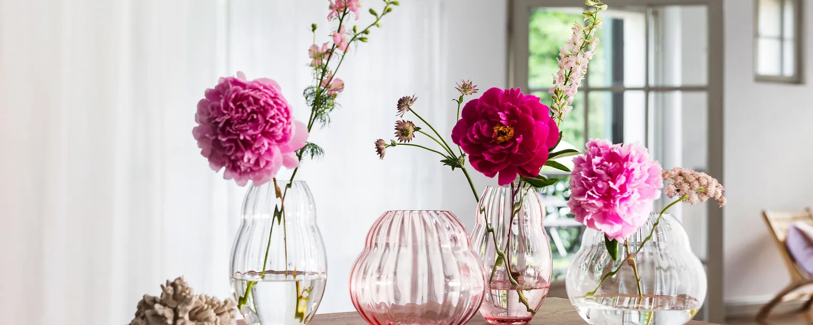 Four different vases from the Villeroy & Boch Rose Garden collection standing on a wooden table.