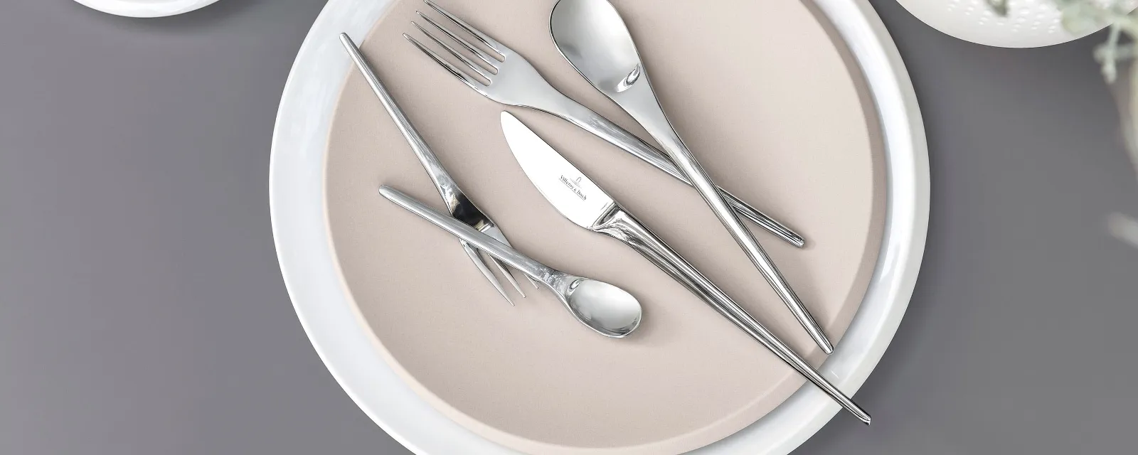 Villeroy & Boch NewMoon table cutlery on a beige plate on a grey background.