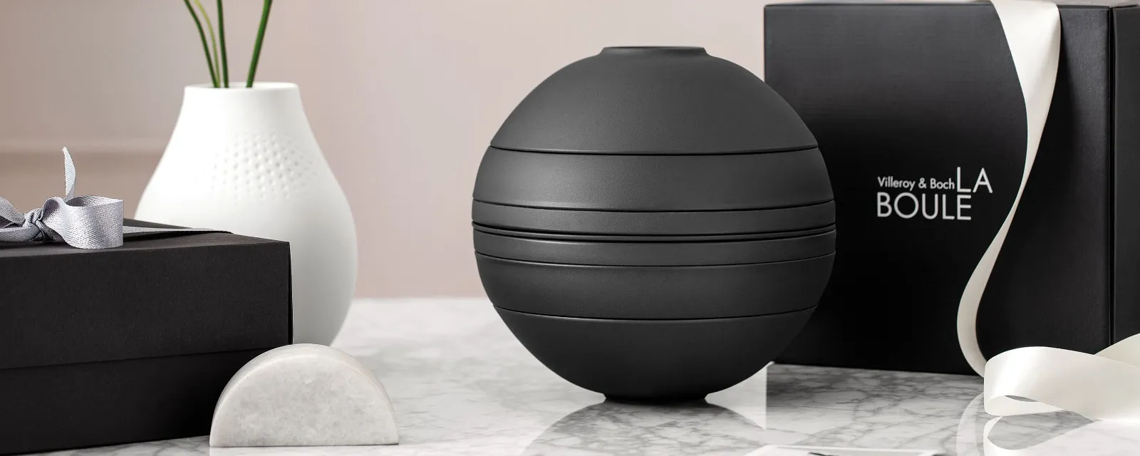 A black La Boule tableware set on a table with a black gift box behind it.