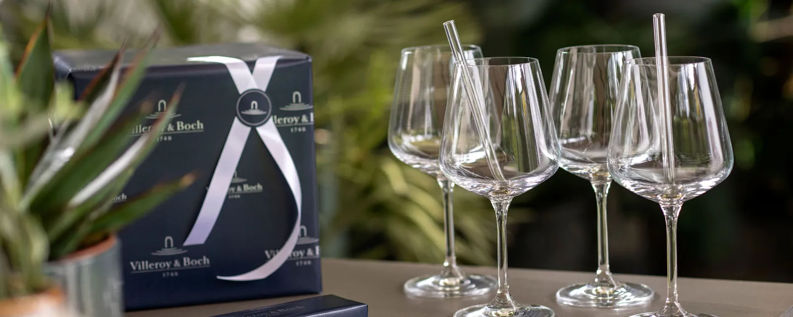 A group of Ovid wine glasses with Purismo glass straws on a table.