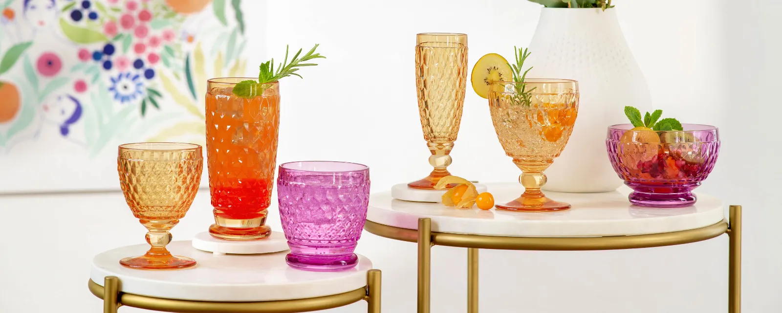 Colourful summer drinks in various Boston glasses on a stylish serving table with a flower painting in the background.