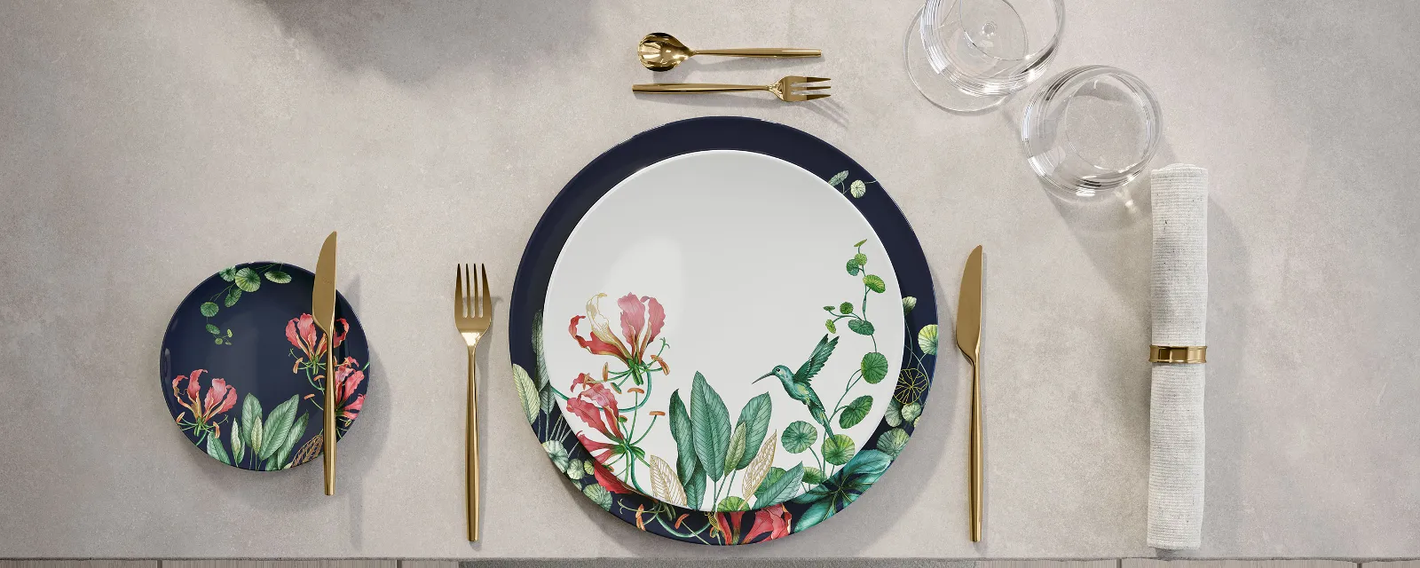 A table setting with floral patterned Avarua crockery and golden MetroChic cutlery.