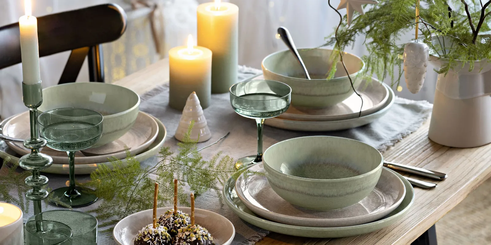 Festive table with green and beige Perlemor plates, surrounded by Winter Glow candleholders and Like glasses.