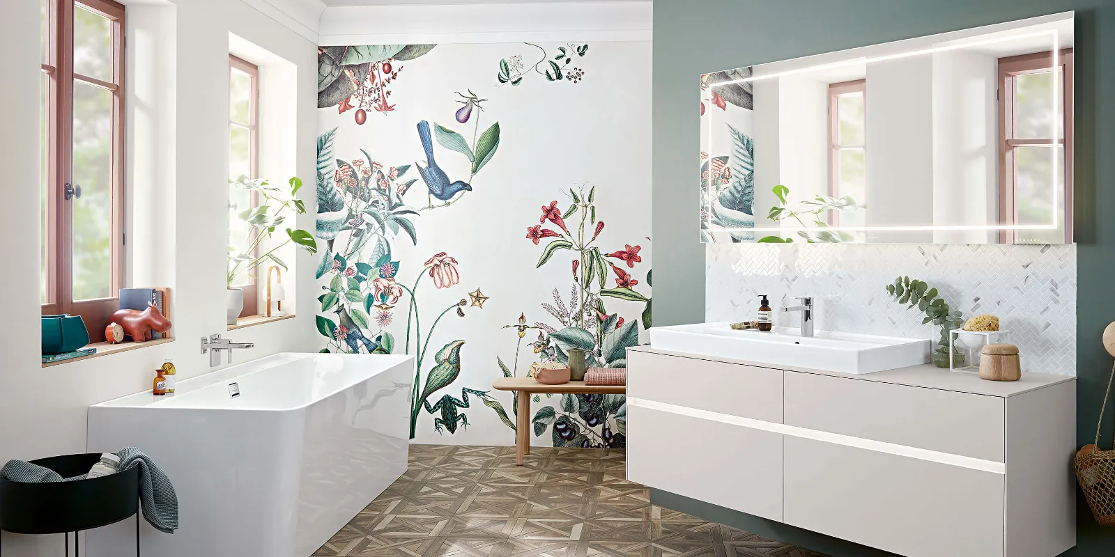 A Collaro washbasin, furniture and bath in a bathroom with floral wallpaper.