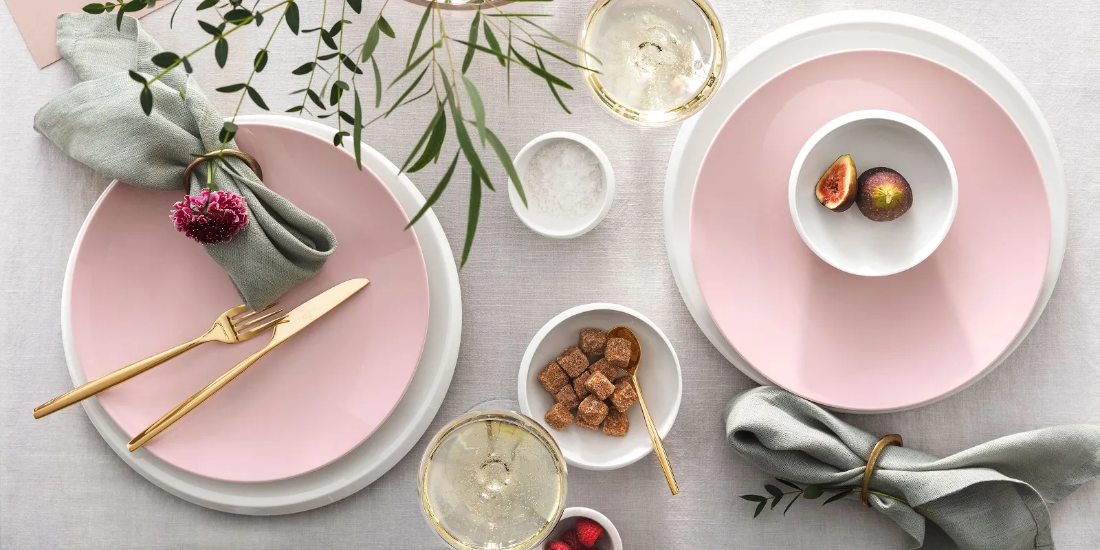 Elegant table decoration with pink Rose Garden plates, gold MetroChic cutlery, fresh flowers and a touch of green, along with drinks and light snacks.