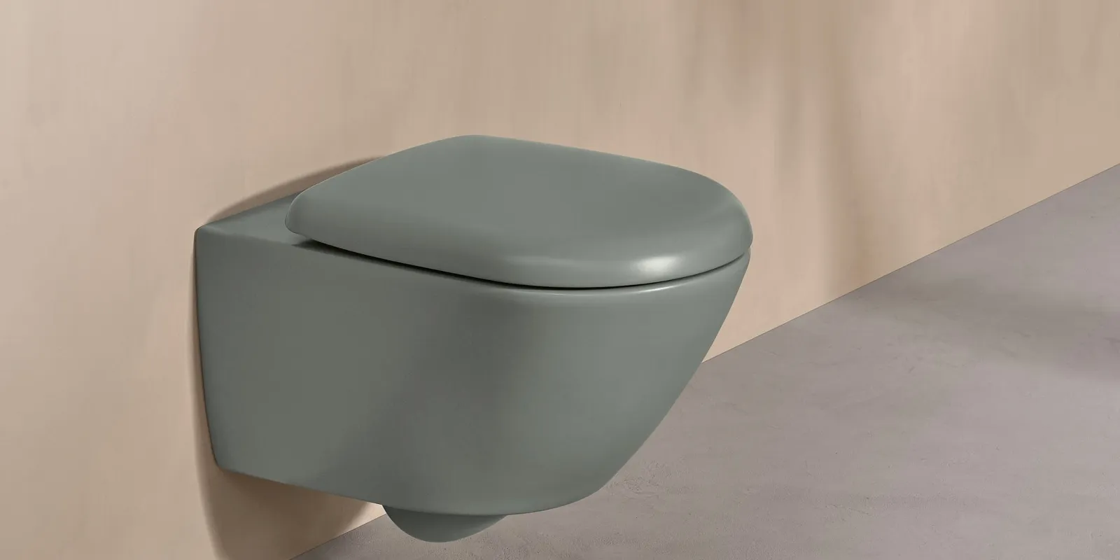 A Villeroy & Boch toilet from the Antao collection in green with a white control panel on a natural-coloured wall.