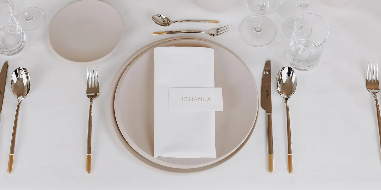 A festive table setting with white and beige NewMoon plates, Ella cutlery and NewMoon glasses.