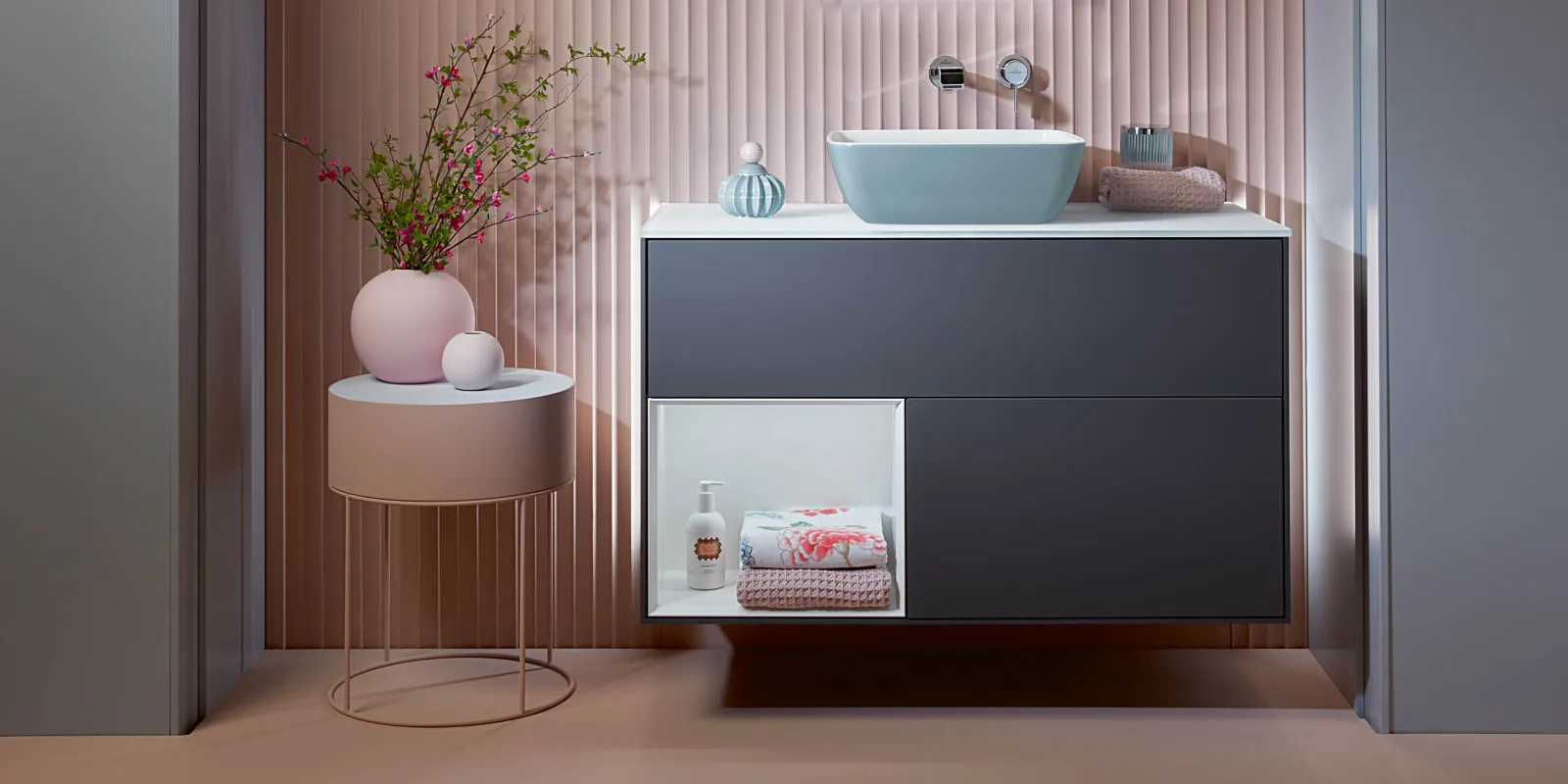 Finion dark-blue vanity unit by Villeroy & Boch in a pink bathroom with a pink coffee table.