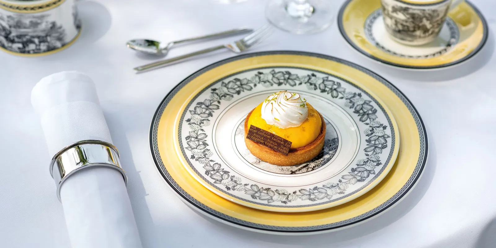 A small dessert with yellow topping and whipped cream on a decorative plate from the Audun collection by Villeroy & Boch. 