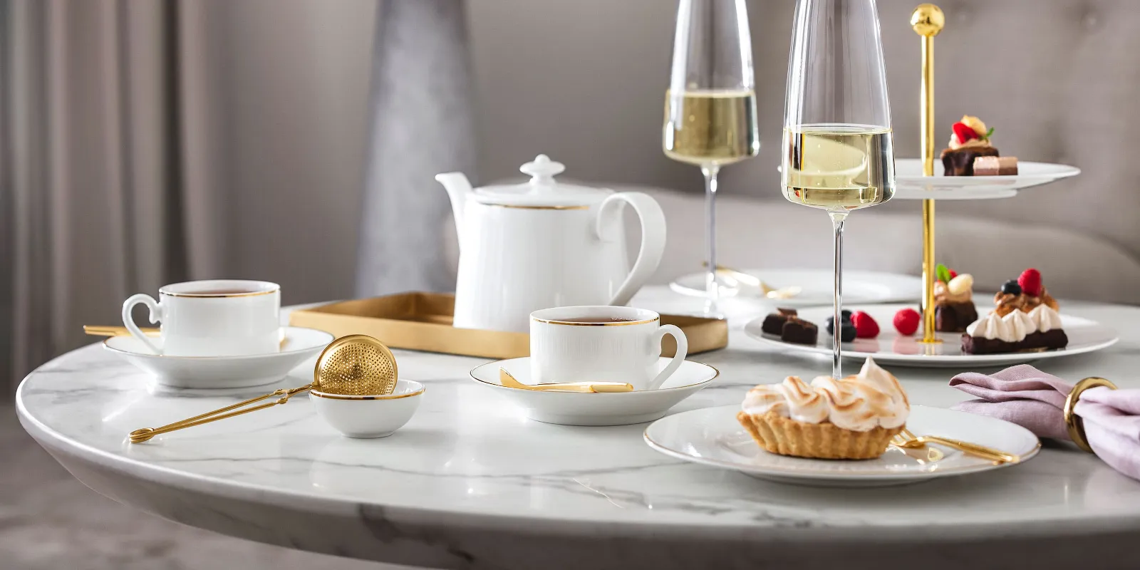 Elegant afternoon tea setting with desserts and champagne on a marble table, served on Château Septfontaines crockery and in MetroChic glasses.