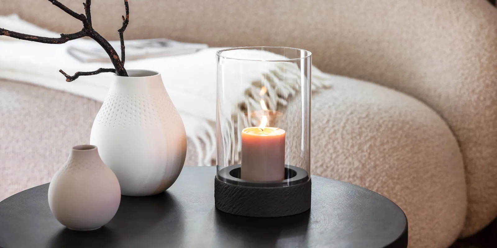 A Manufacture candle standing on a table next to two Manufacture vases.