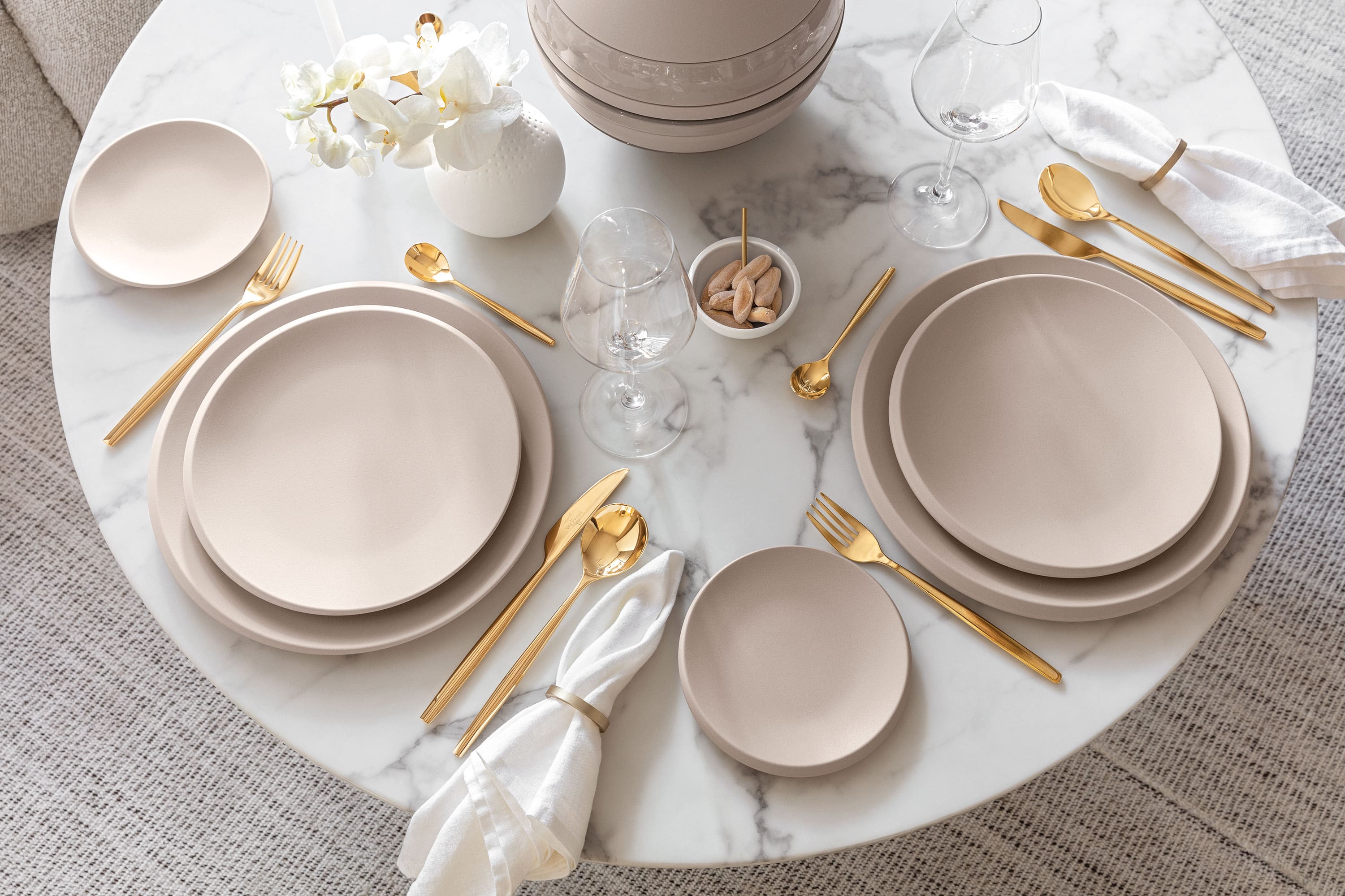 A table set with Villeroy & Boch beige NewMoon plates and gold MetroChic cutlery