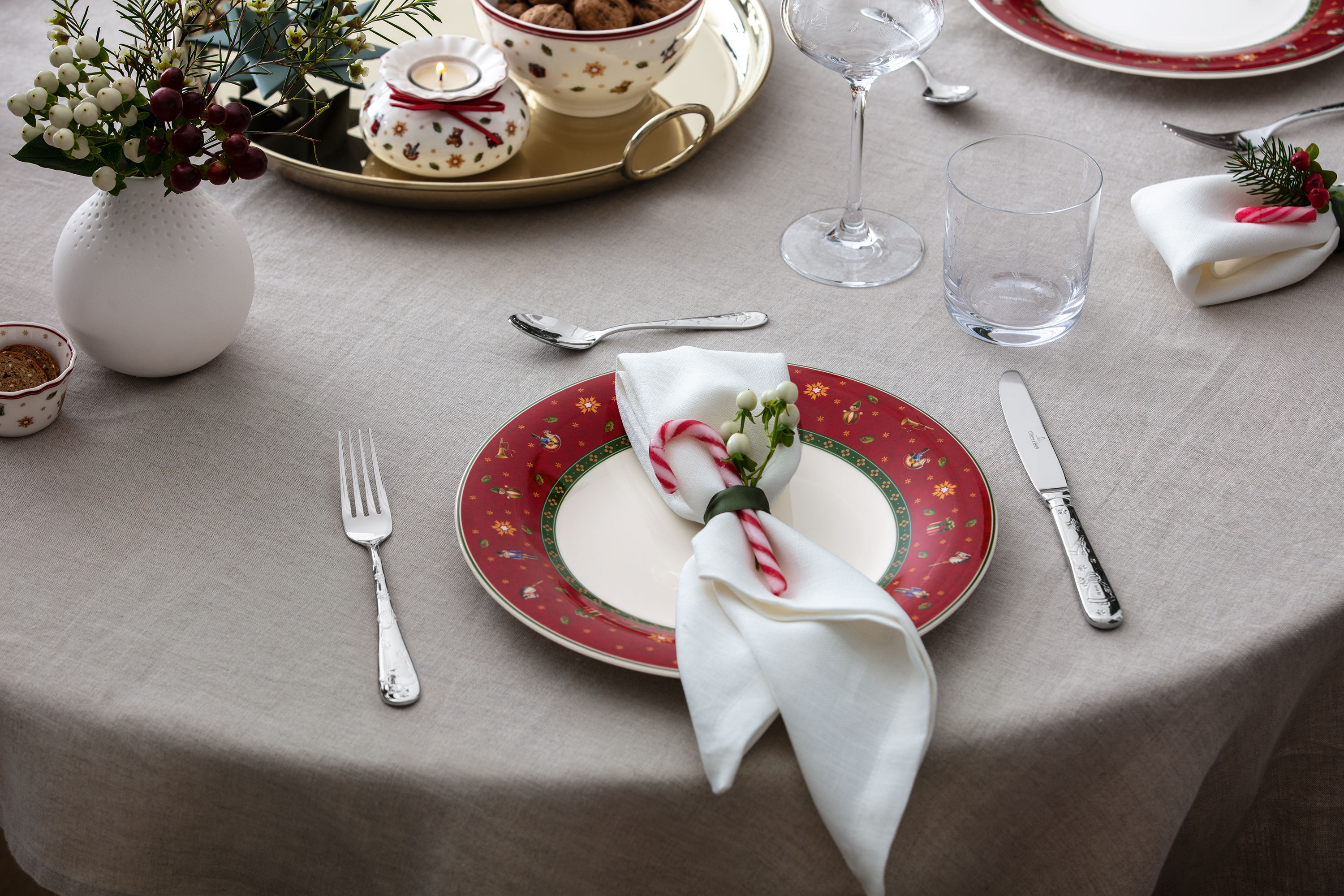 Une assiette rouge festive Toys Delight associée à un photophore, parfaite pour une table de Noël chaleureuse.