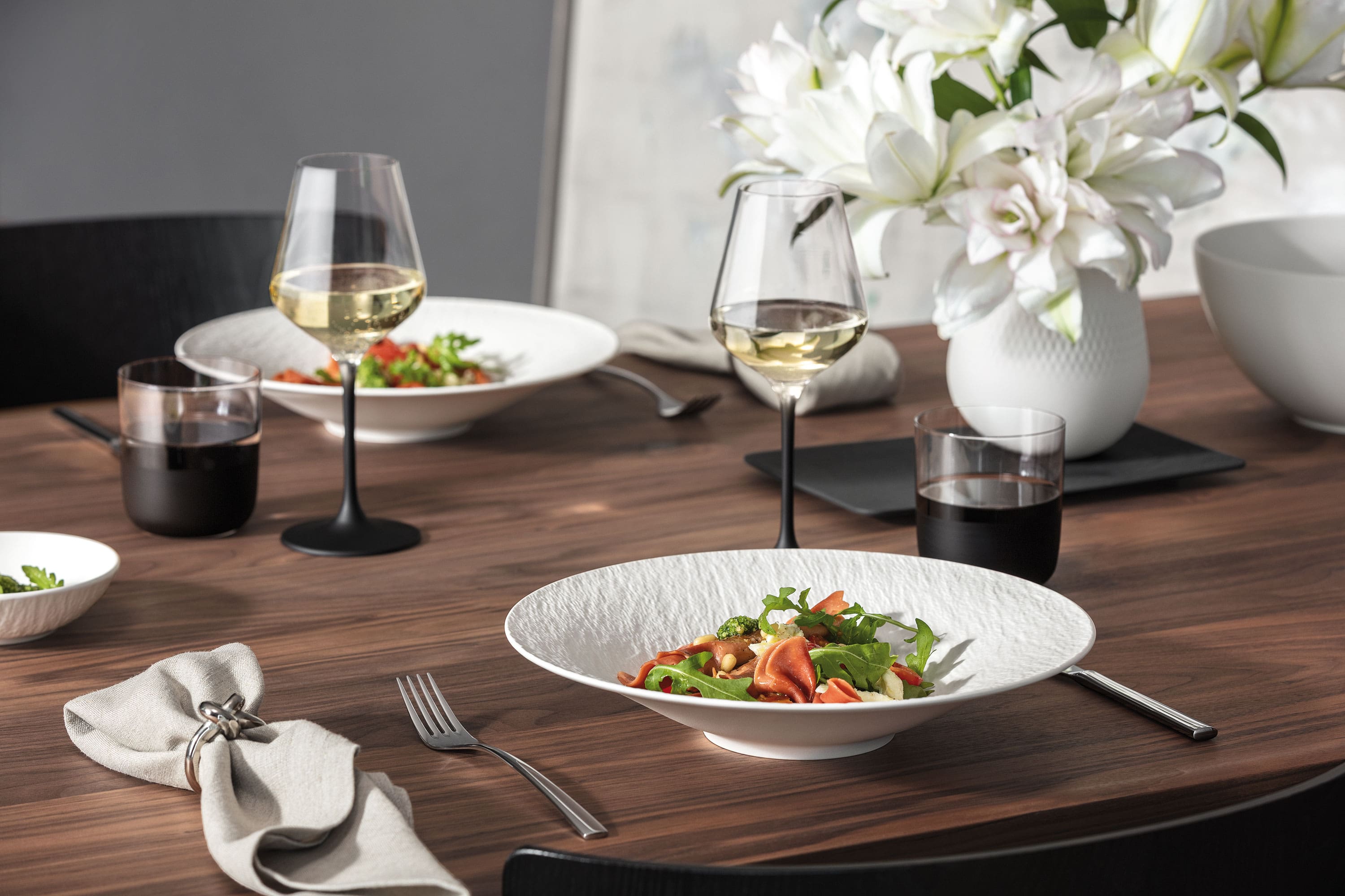 A contemporary Manufacture Rock Blanc tableware set paired with a matching Carré vase with flowers for a clean, modern table setting.