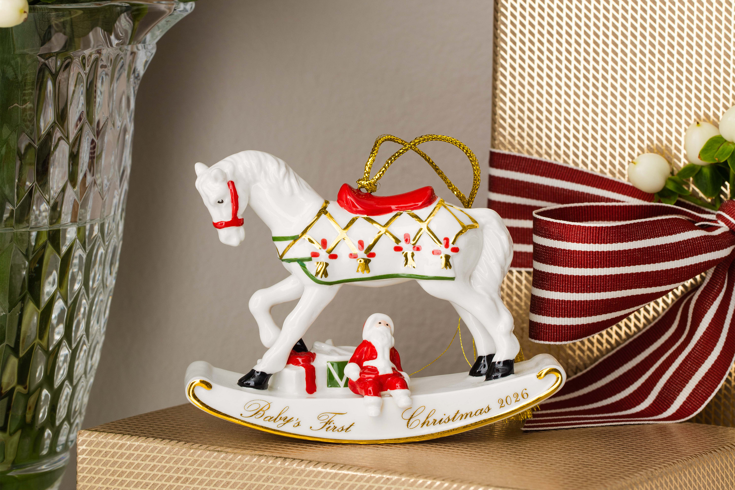 Christmas Classics Rocking Horse Ornament A porcelain rocking horse ornament featuring the inscription ‘Baby's First Christmas 2020’ alongside wrapped presents and a vase of flowers.