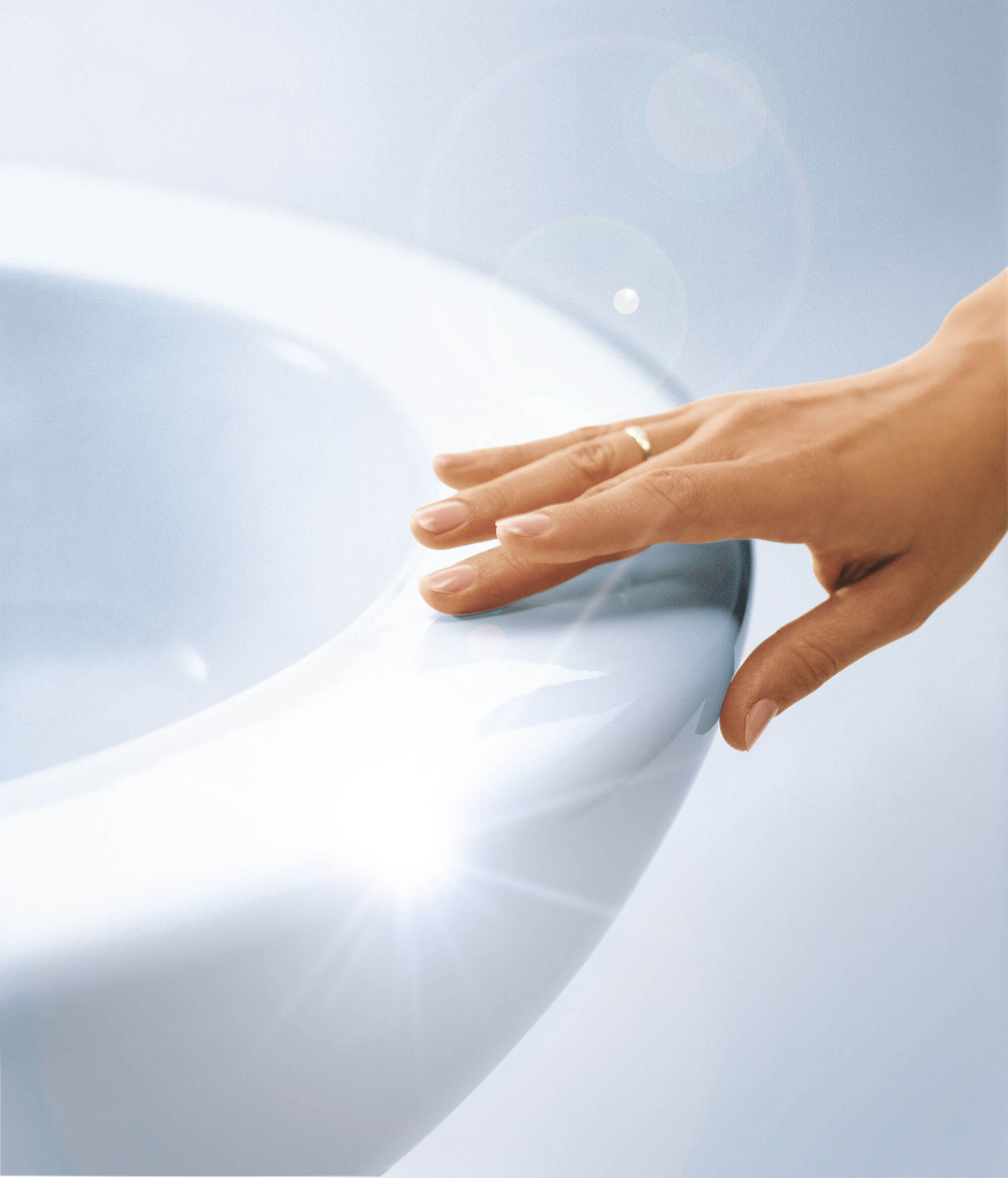 Hand berührt CeramicPlus Toilette Nahaufnahme einer Hand mit einem goldenen Ring, die den Rand eines weißen, glänzenden Keramik-WCs berührt.