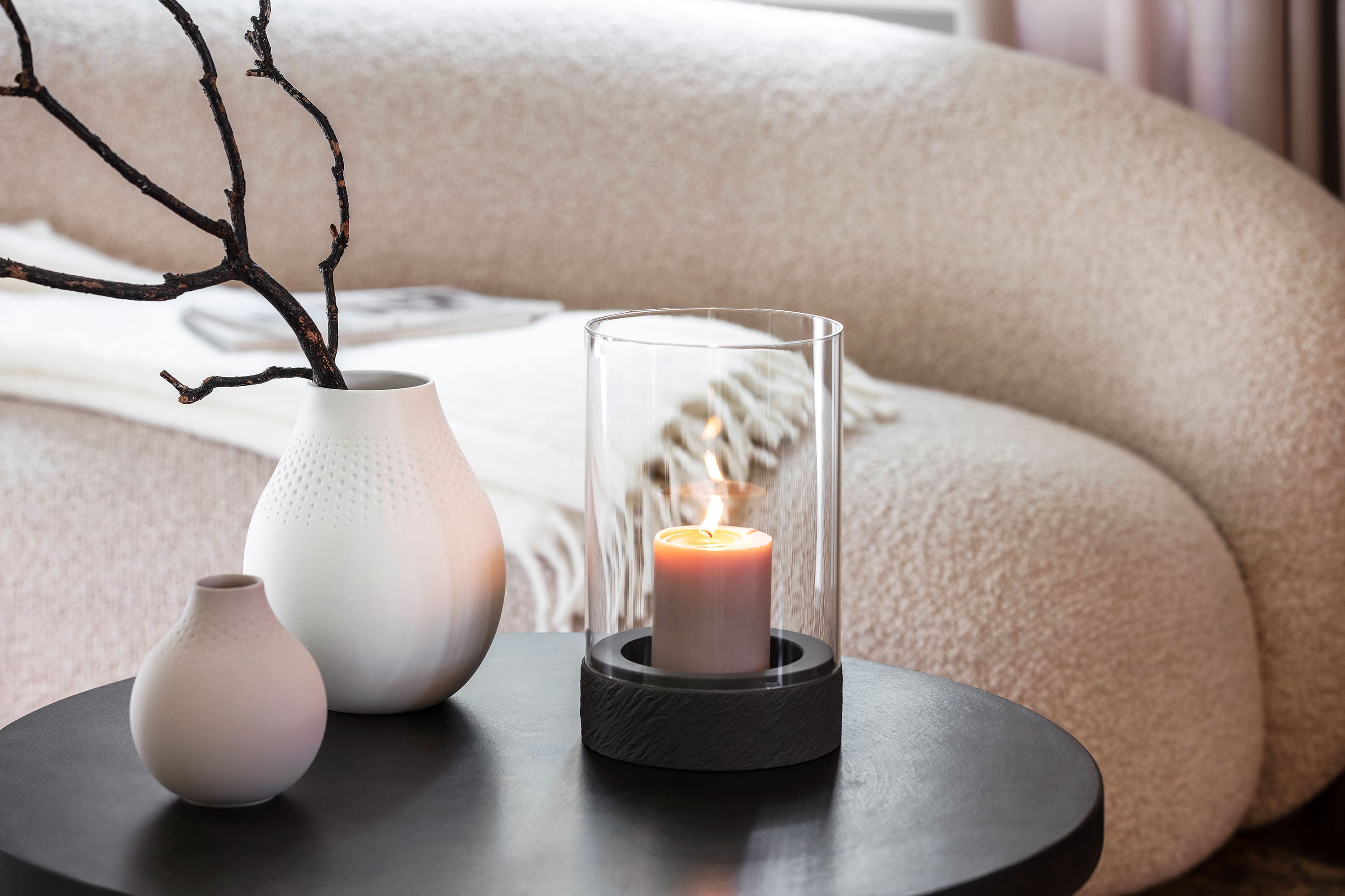 A Manufacture candle standing on a table next to two Manufacture vases.