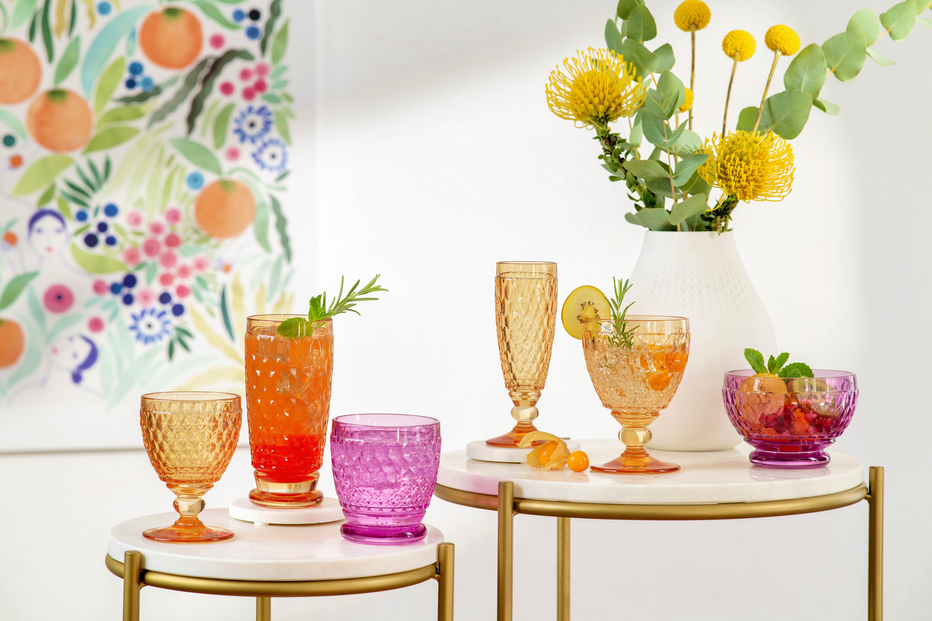 Colorful summer drinks in various Boston glasses on a chic serving table with a flower painting in the background.