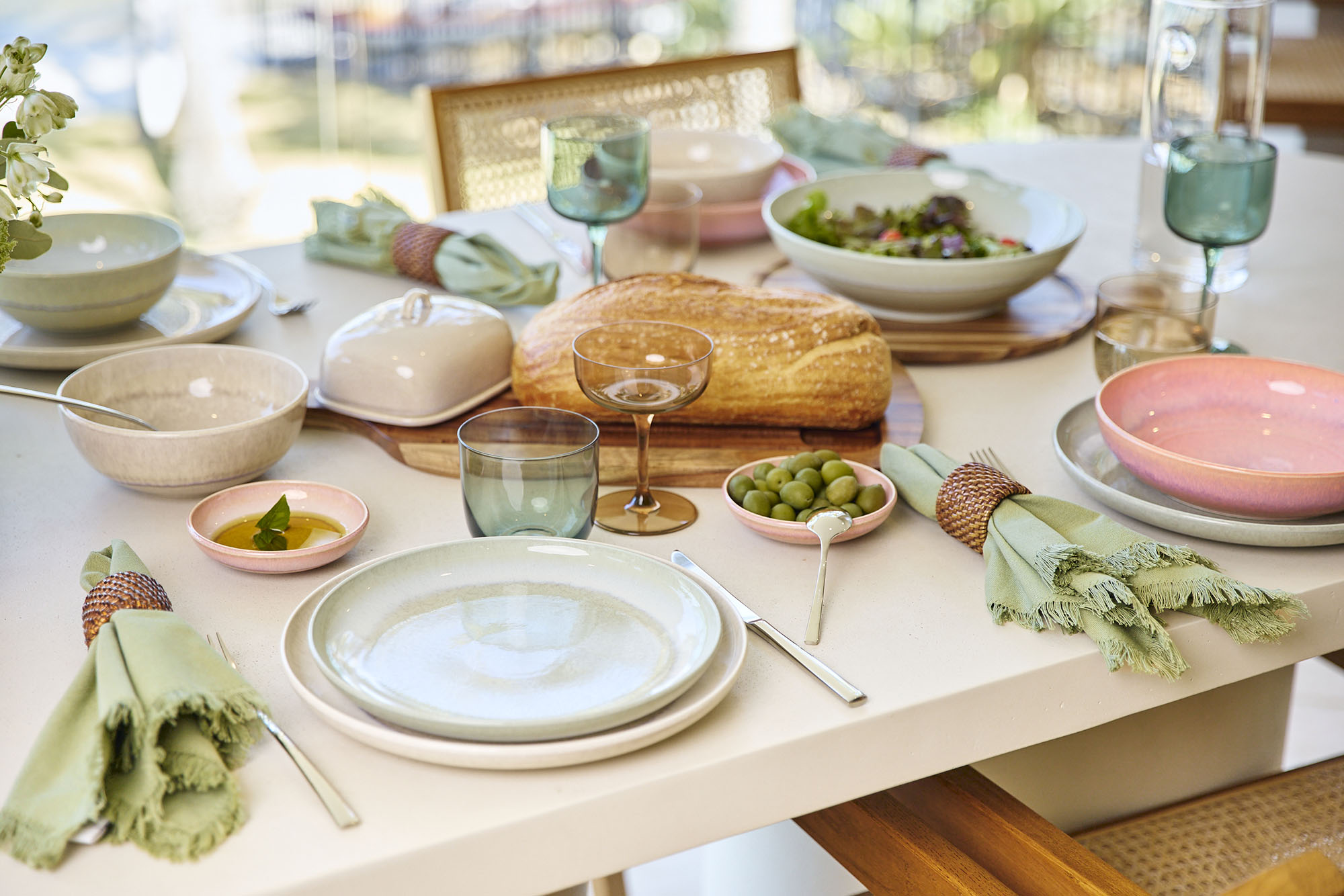 Una tavola apparecchiata con piatti, bicchieri, pane, insalata e tovaglioli per un pasto.