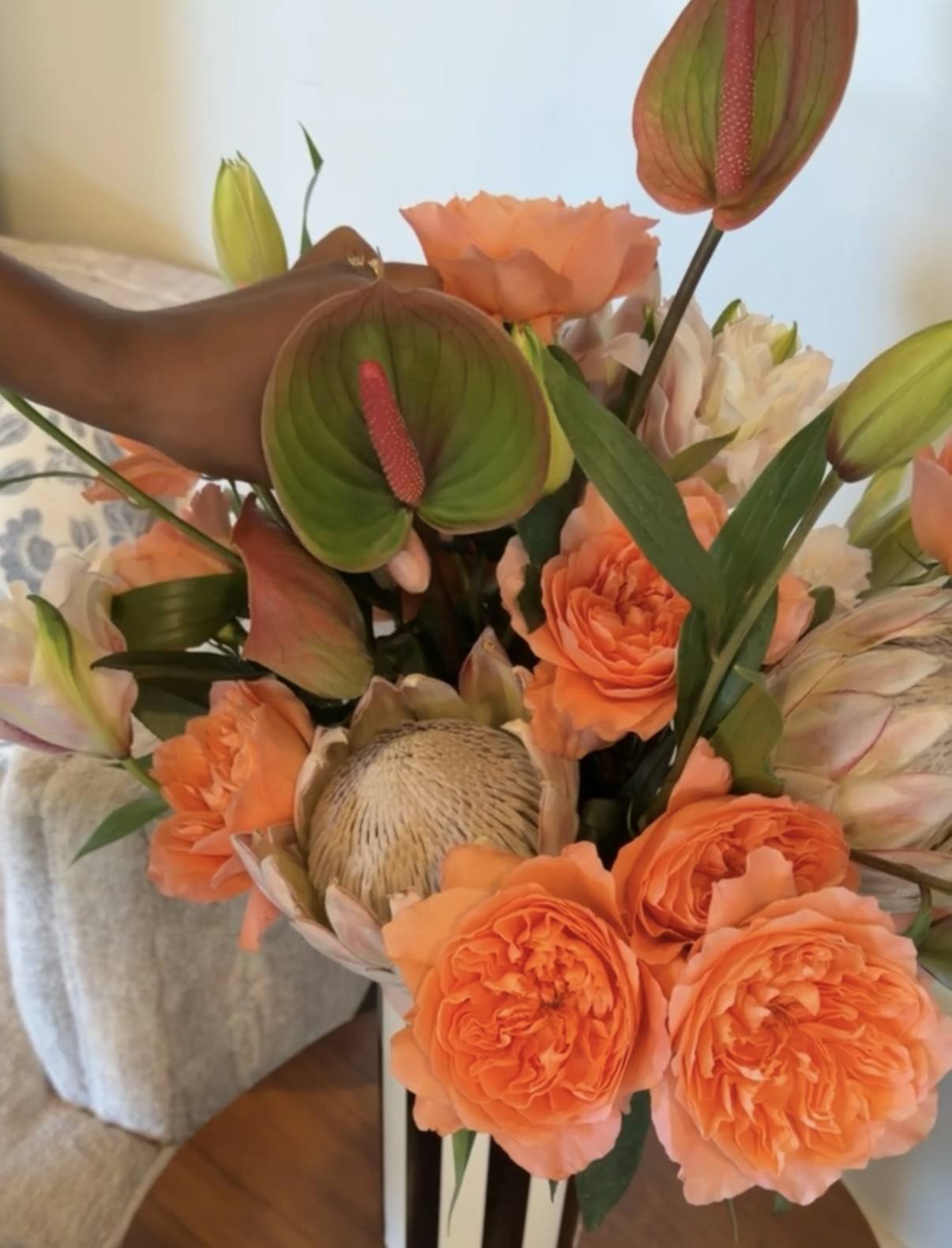 Anthurium Flowers Vibrant floral bouquet with orange roses and carnations, green anthuriums, protea, and pale blooms, creating a warm, joyful mood.